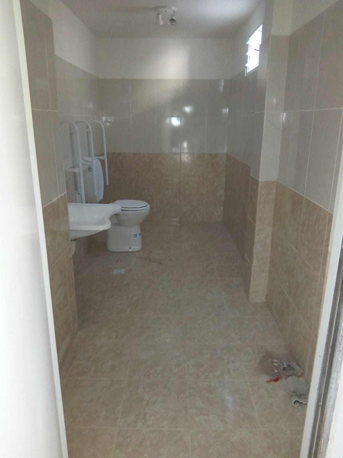 Baño adaptado con baranda de seguridad y cerámico accesible